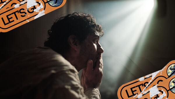 Isaiah covers his mouth with his hands as a beam of light shines on him